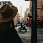 View of Eiffel Tower from a Paris street with a scooter and pedestrian.